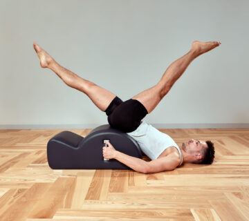 Man performing classical Pilates spine corrector exercise at Fit N Pilates studio in Plano, Texas