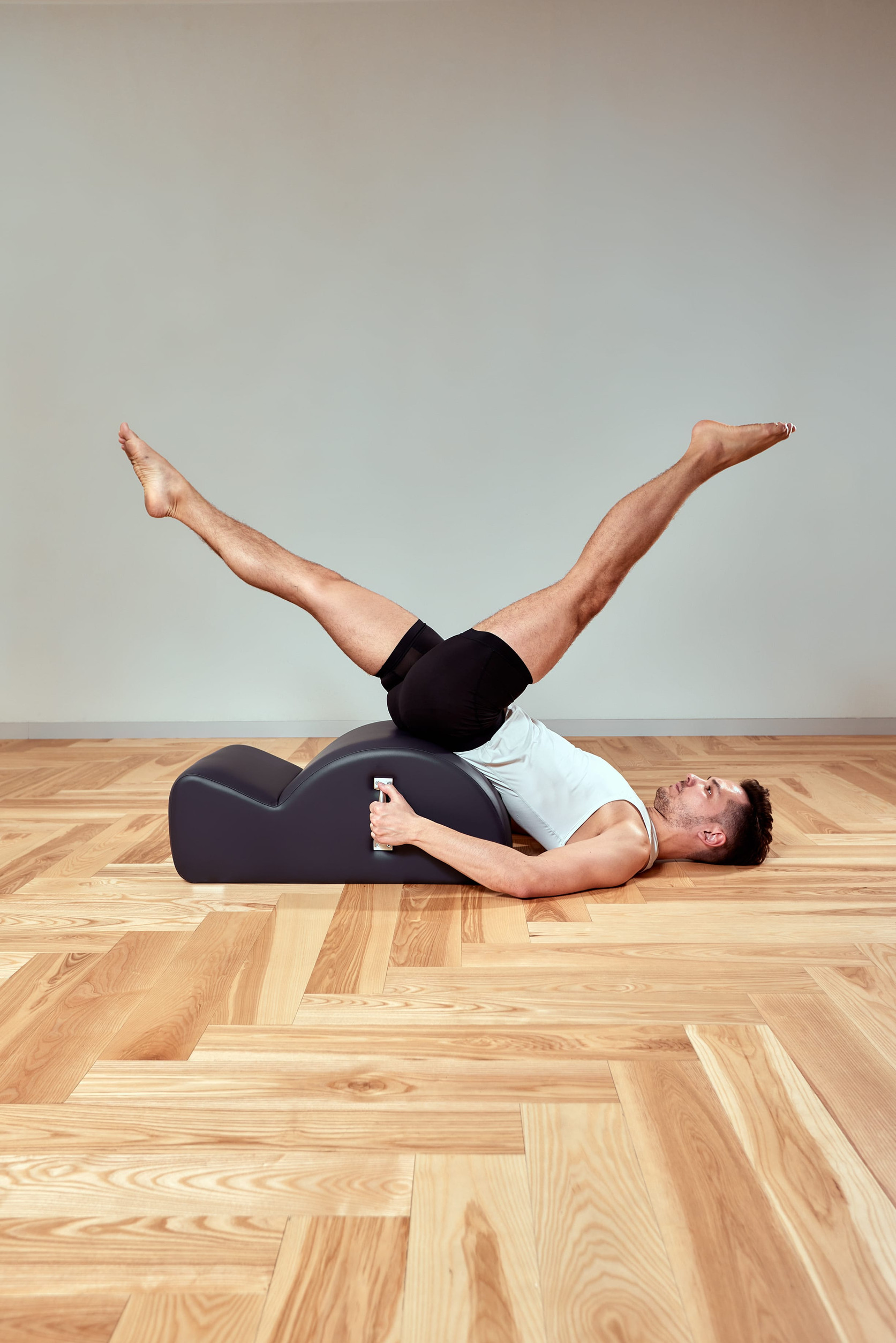 Man performing classical Pilates spine corrector exercise at Fit N Pilates studio in Plano, Texas